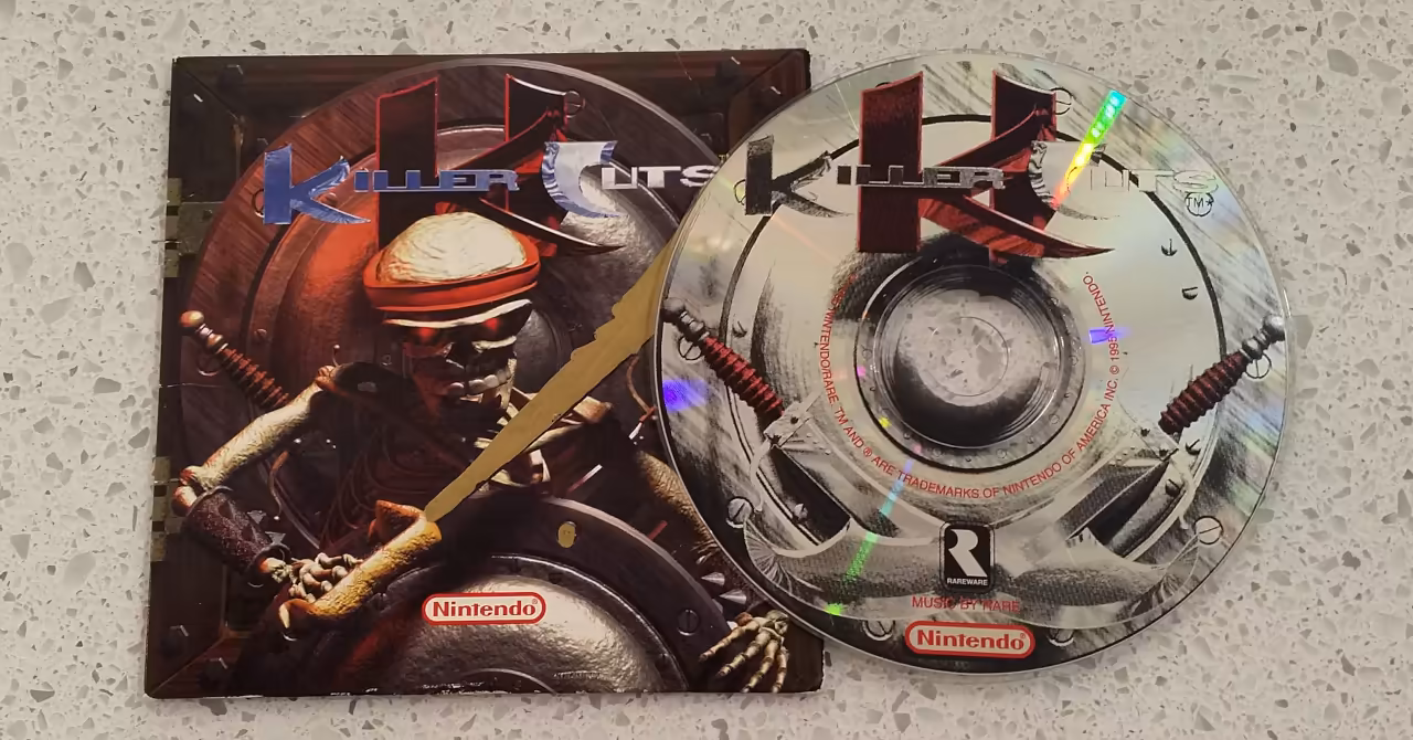 Killer Instinct Killer Cuts music CD and cardboard sleeve on display on a stone bench