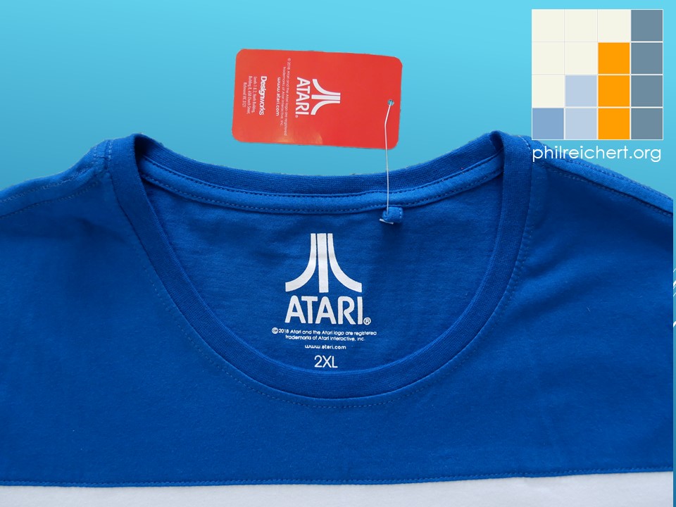 Interior neckline of the Atari T-shirt showing the printed Atari logo, size marking, and attached red Atari authenticity swing tag